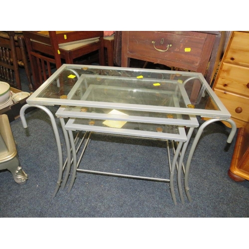 919 - A SMALL SILVER FOUR DRAWER CHEST PLUS A NEST OF GLASS / METAL TABLES (2)