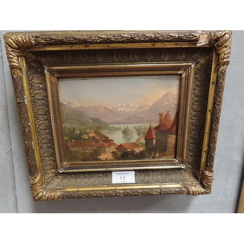 11 - A GILT FRAMED SMALL OIL ON CARD OF A MOUNTAINOUS LAKESIDE VILLAGE