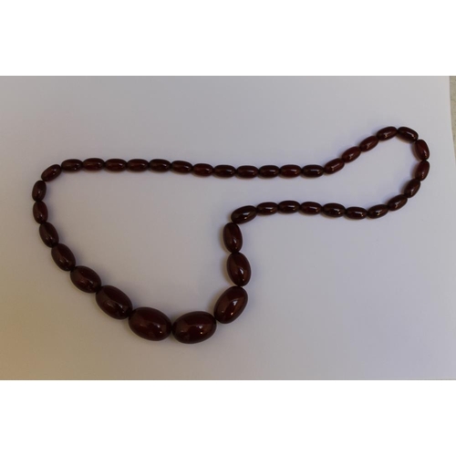 261 - A STRING OF GRADUATING CHERRY AMBER BEADS, largest W 2.5 cm