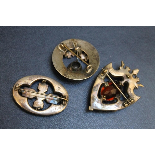 262 - THREE SCOTTISH THEMED BROOCHES, consisting of an oval hardstone example set in hallmarked silver (ha... 