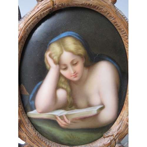 67 - A 19TH CENTURY CONTINENTAL OVAL PORCELAIN PLAQUE OF A LADY READING, unsigned in a carved wooden fram... 