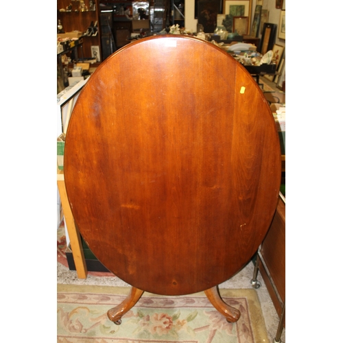 869 - A MAHOGANY TILT TOP OVAL TABLE ON CARVED BASE