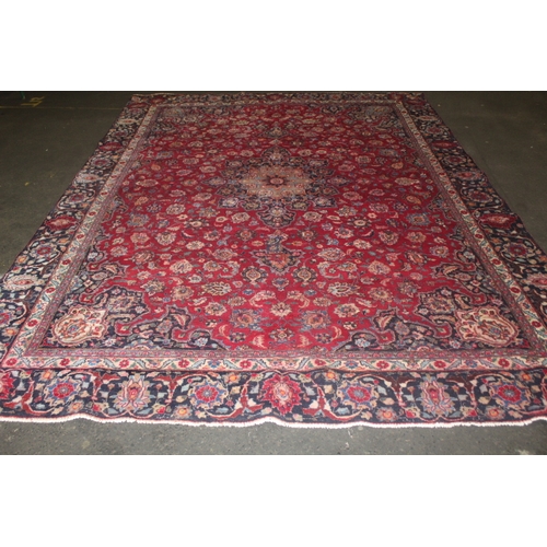 849 - A LARGE EASTERN WOOLLEN RUG IN MAINLY RED AND BLACK PATTERN 377 X 275 CM