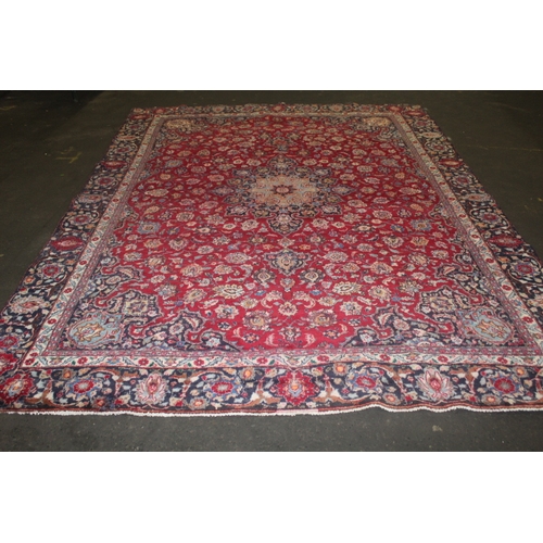 849 - A LARGE EASTERN WOOLLEN RUG IN MAINLY RED AND BLACK PATTERN 377 X 275 CM