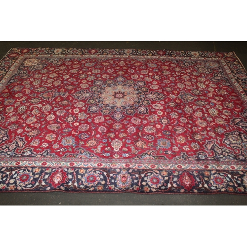 849 - A LARGE EASTERN WOOLLEN RUG IN MAINLY RED AND BLACK PATTERN 377 X 275 CM