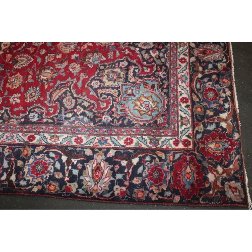 849 - A LARGE EASTERN WOOLLEN RUG IN MAINLY RED AND BLACK PATTERN 377 X 275 CM