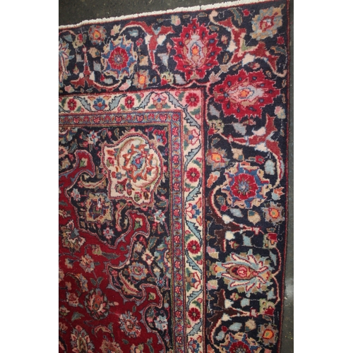 849 - A LARGE EASTERN WOOLLEN RUG IN MAINLY RED AND BLACK PATTERN 377 X 275 CM