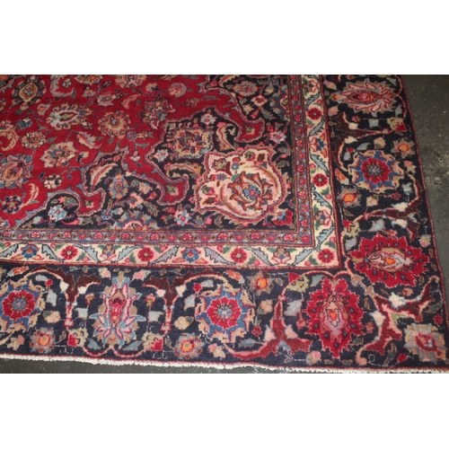 849 - A LARGE EASTERN WOOLLEN RUG IN MAINLY RED AND BLACK PATTERN 377 X 275 CM