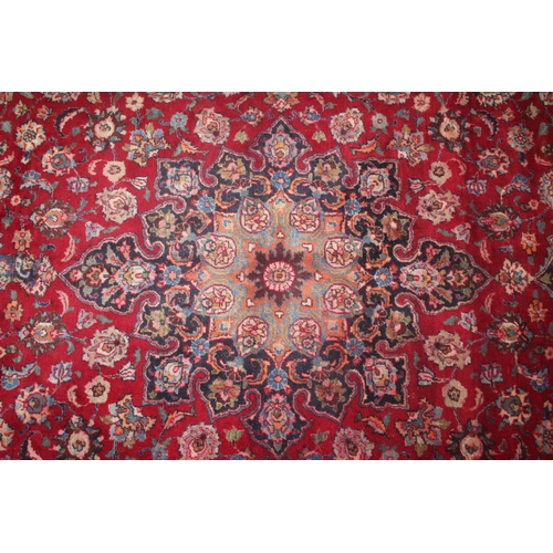 849 - A LARGE EASTERN WOOLLEN RUG IN MAINLY RED AND BLACK PATTERN 377 X 275 CM