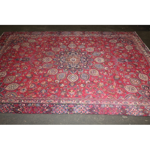 850 - A LARGE EASTERN WOOLLEN RUG IN MAINLY RED AND BLACK PATTERN 362 X 269 CM