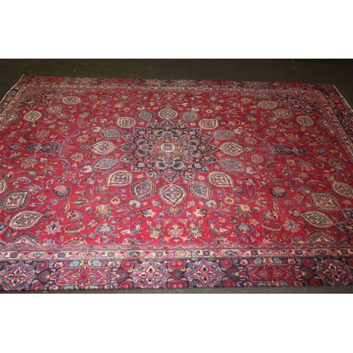 850 - A LARGE EASTERN WOOLLEN RUG IN MAINLY RED AND BLACK PATTERN 362 X 269 CM