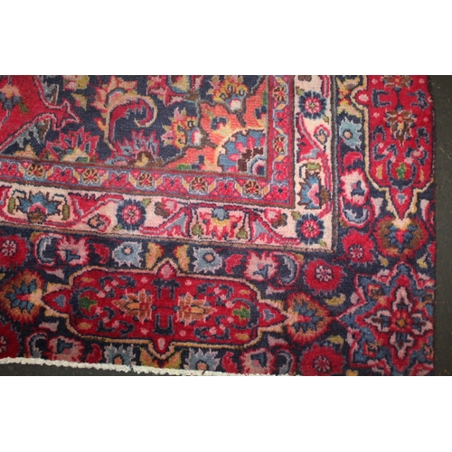 850 - A LARGE EASTERN WOOLLEN RUG IN MAINLY RED AND BLACK PATTERN 362 X 269 CM