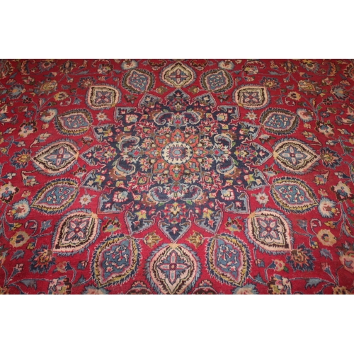 850 - A LARGE EASTERN WOOLLEN RUG IN MAINLY RED AND BLACK PATTERN 362 X 269 CM