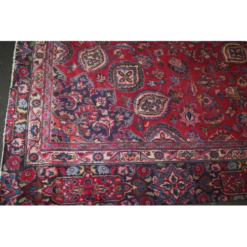 850 - A LARGE EASTERN WOOLLEN RUG IN MAINLY RED AND BLACK PATTERN 362 X 269 CM