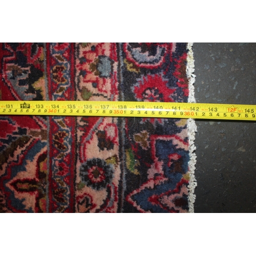 850 - A LARGE EASTERN WOOLLEN RUG IN MAINLY RED AND BLACK PATTERN 362 X 269 CM