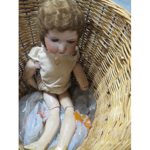 154 - A VINTAGE ARMAND MARSEILLE CERAMIC HEADED DOLL CONTAINED IN A WICKER BASKET