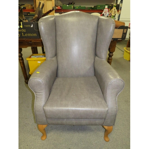 761 - AN UPHOLSTERED WING ARMCHAIR A/F