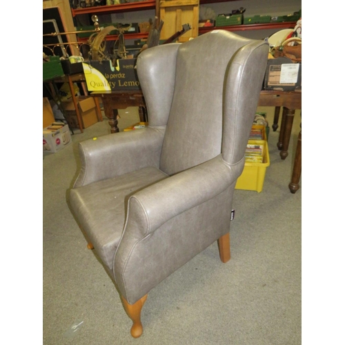 761 - AN UPHOLSTERED WING ARMCHAIR A/F