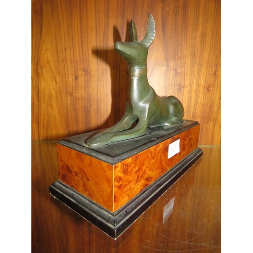 247 - A BRONZE TYPE MODEL OF AN EGYPTIAN STYLE DOG ON A WALNUT EFFECT PLINTH