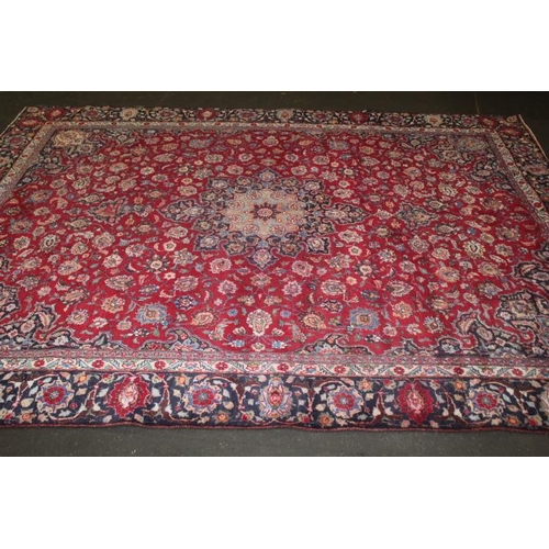 829 - A LARGE EASTERN WOOLLEN RUG IN MAINLY RED AND BLACK PATTERN 377 x 275 cm