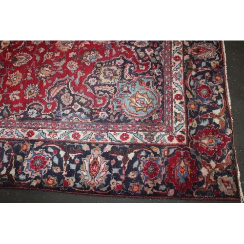 829 - A LARGE EASTERN WOOLLEN RUG IN MAINLY RED AND BLACK PATTERN 377 x 275 cm