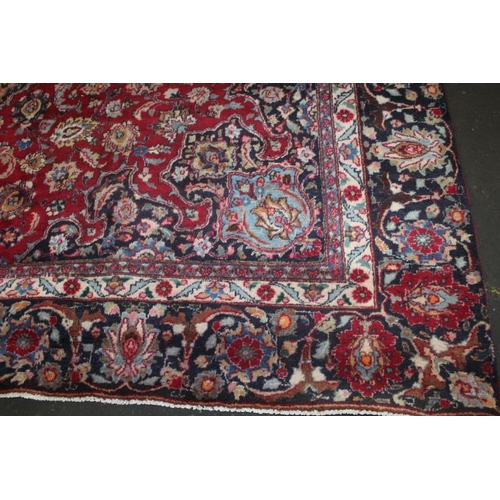 829 - A LARGE EASTERN WOOLLEN RUG IN MAINLY RED AND BLACK PATTERN 377 x 275 cm