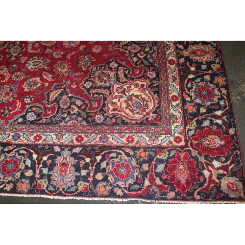 829 - A LARGE EASTERN WOOLLEN RUG IN MAINLY RED AND BLACK PATTERN 377 x 275 cm