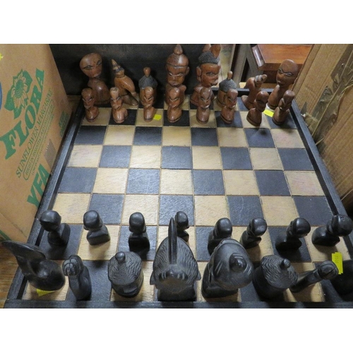 103 - A CARVED WOODEN CHESS SET AND BOARD DEPICTING AFRICAN STYLISED PIECES