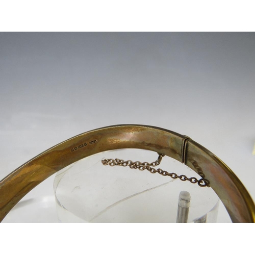 146 - A HALLMARKED 9CT GOLD HINGED BANGLE, with engraved embellishment to one side and with safety chain, ... 