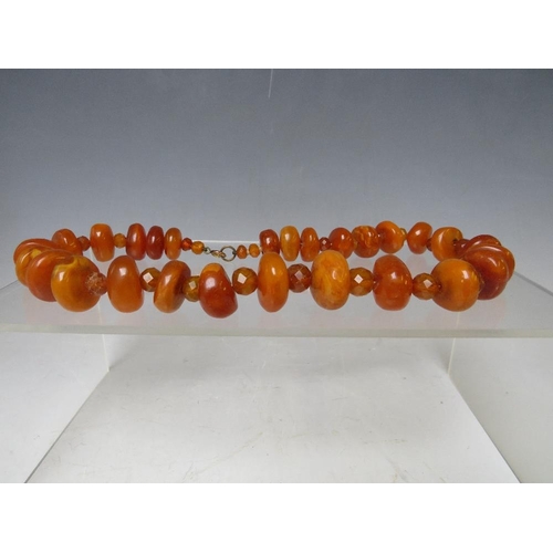 164 - AN UNUSUAL VINTAGE AMBER BEAD NECKLACE, the chunky disc shaped amber bead interspersed with small fa... 