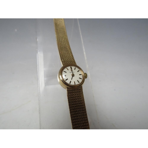 180 - AN OMEGA 9CT GOLD LADIES MANUAL WIND WRISTWATCH, with integral mesh strap, champagne dial with baton... 