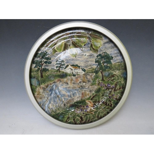 357 - A LARGE COBRIDGE CIRCULAR CHARGER BY ANJI DAVENPORT, decorated with a country house by a stream, imp... 