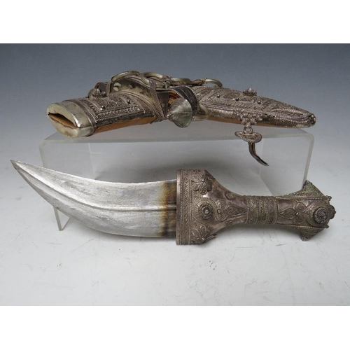 427 - A VINTAGE MIDDLE EASTERN JAMBYA DAGGER, with white metal handled accoutrements and leather covered s... 