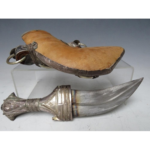 427 - A VINTAGE MIDDLE EASTERN JAMBYA DAGGER, with white metal handled accoutrements and leather covered s... 