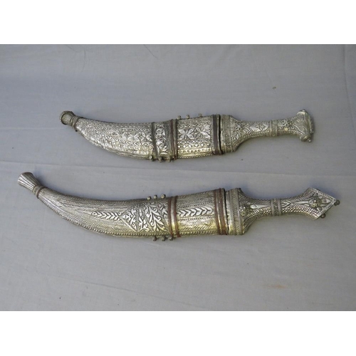 432 - FOUR MIDDLE EASTERN JAMBIYA DAGGERS, all with typical curved blades and sheet white metal decoration