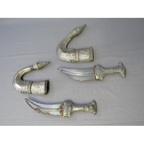 432 - FOUR MIDDLE EASTERN JAMBIYA DAGGERS, all with typical curved blades and sheet white metal decoration