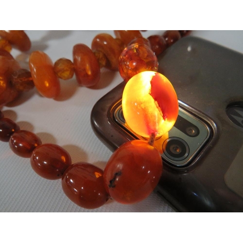 375 - AN UNUSUAL VINTAGE AMBER BEAD NECKLACE, the chunky disc shaped amber bead interspersed with small fa... 