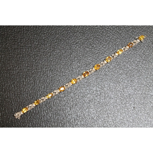 89 - AN UNMARKED WHITE METAL GEM SET BRACELET, set with eleven citrine style stones and diamonds on a box... 