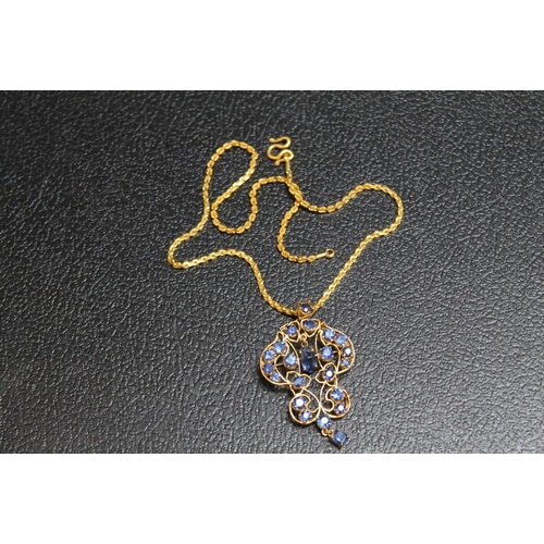 111 - AN ORNATE SAPPHIRE PENDANT, set in unmarked yellow metal and on a similar chain with simple s link f... 