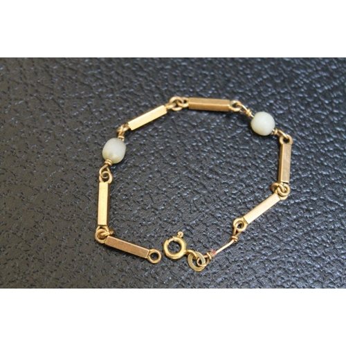 130 - A SMALL CHILD'S GOLD BRACELET, stamped 750 and having two pearl separators - both damaged, approx we... 