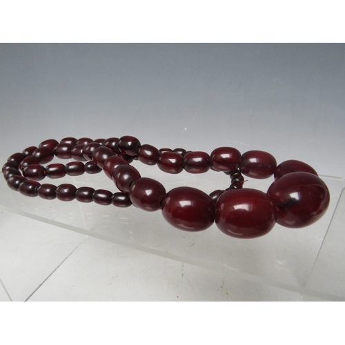 58 - A CHERRY RED FATURAN AMBER GRADUATED OVAL BEAD NECKLACE, approx L 68 cm, approx weight 63 g