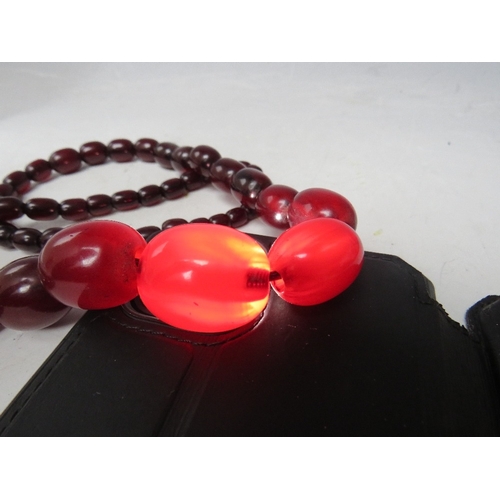 58 - A CHERRY RED FATURAN AMBER GRADUATED OVAL BEAD NECKLACE, approx L 68 cm, approx weight 63 g