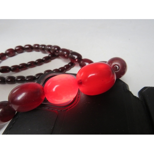 58 - A CHERRY RED FATURAN AMBER GRADUATED OVAL BEAD NECKLACE, approx L 68 cm, approx weight 63 g