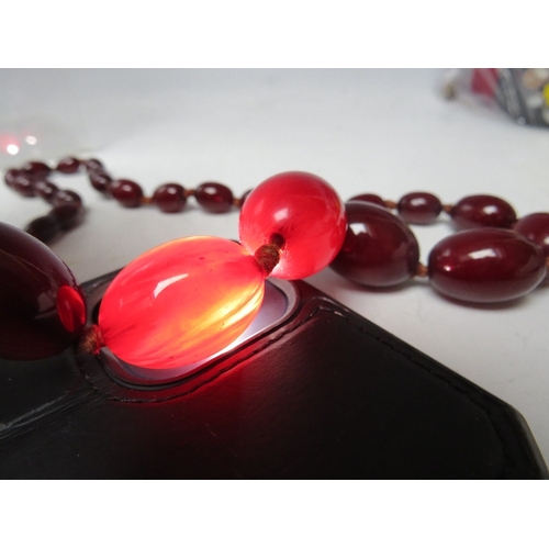 59 - A CHERRY RED FATURAN AMBER GRADUATED OVAL BEAD NECKLACE, approx L 70 cm, approx weight 51 g