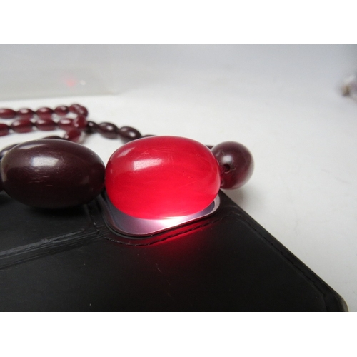 60 - A CHERRY RED FATURAN AMBER GRADUATED OVAL BEAD NECKLACE, approx L 54 cm, approx weight 39 g