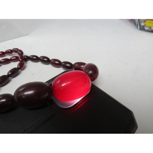 60 - A CHERRY RED FATURAN AMBER GRADUATED OVAL BEAD NECKLACE, approx L 54 cm, approx weight 39 g