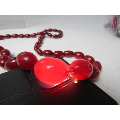 61 - A CHERRY RED FATURAN AMBER GRADUATED OVAL BEAD NECKLACE, approx L 59 cm, approx weight 40 g