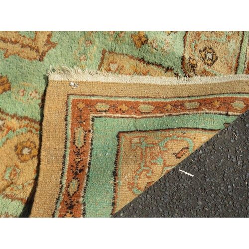 720 - A large late 19th/early 20th century woollen rug on a mainly green ground, approximately 295 x 272 c... 