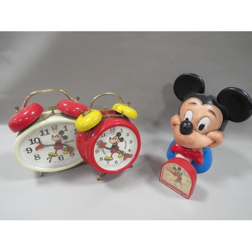 310 - THREE VINTAGE DISNEY MICKY MOUSE CLOCKS TOGETHER WITH A PLASTIC MONEY BOX (NO STOPPER )