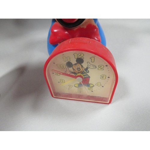 310 - THREE VINTAGE DISNEY MICKY MOUSE CLOCKS TOGETHER WITH A PLASTIC MONEY BOX (NO STOPPER )